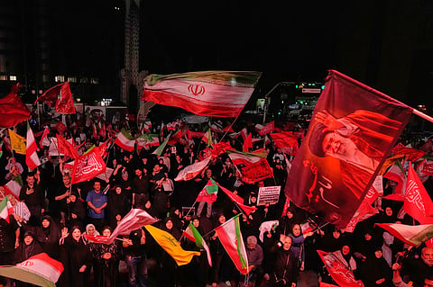 Pro-government demonstrators wave Iranian and religious flags in a gathering commemorating the late Iranian Supreme Leader Ayatollah Ali Khamenei, shown in a flag at right, at a square in Tehran, Saturday, July 11, 2026.