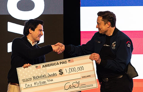 FILE - Elon Musk hands over a million dollar check to Nicholas Jacobs during a town hall in Green Bay, Wisonsin, March 30, 2025. (AP Photo/Jeffrey Phelps, File)