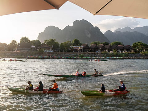 Tourists ride in boats along the Nam Song river in Vang Vieng, Laos.