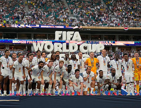 England's Harry Kane (9), front center, gives a thumbs as the team poses with their medals after the World Cup third-place playoff soccer match between France and England in Miami Gardens, Fla..