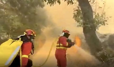 This screen grab of a handout video taken and released on July 24, 2026 by Spain's Military Emergencies Unit (UME) shows firefighters battling a wildfire on a road in Burgohondo area, near Avila, 130 kilometers west of Madrid.