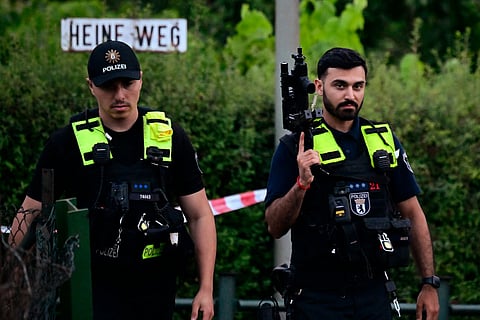 Police officers walk with automatic weapons in an allotment complex in the western Spandau district of Berlin on July 26, 2026, in a garden area near the scene where the chief suspect in the previous nights' deadly attack near Berlin's Pride parade has been shot dead.