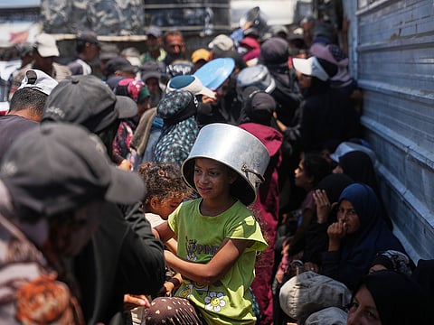 Displaced Palestinians line up to receive donated food at a community kitchen in Khan Younis, southern Gaza Strip, Thursday, July 23, 2026.