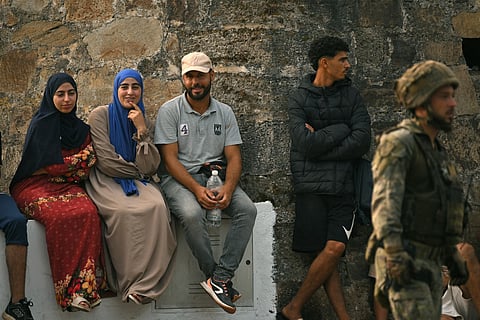 A Spanish soldier walks past a group of migrants prior to escorting them back to Morocco, in Spain's north Africa's Ceuta enclave on August 1, 2026.