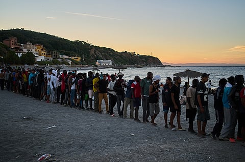 Migrants who crossed from Morocco into Spain line up for food distribution on a beach in the Spanish enclave of Ceuta, Monday, Aug. 3, 2026.