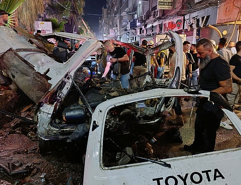 Syrian security personnel inspect damaged vehicles at the site of an explosion in the Jaramana suburb.