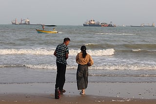 Iranians enjoy the seaside as vessels are seen in the Strait of Hormuz off Bandar Abbas, in southern Iran on August 10, 2026.