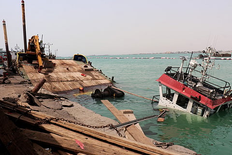 The navigation bridge of a sunken vessel protrudes from the water at the Port of Mocha, a day after a Houthi attack on the city on August 10, 2026.