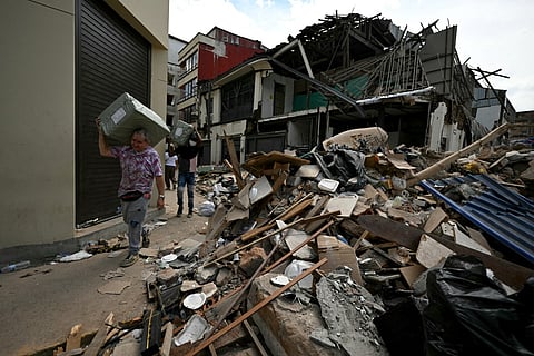 People carry boxes amid the rubble of a collapsed building four days after a 7.4 earthquake in Pereira, Colombia on August 14, 2026.