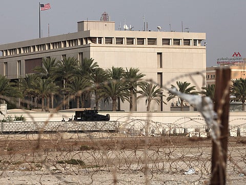 A Bahraini armored personnel vehicle and personnel reinforce US Embassy security just outside of a gate to the building, surrounded in barbed wire, in Manama, Bahrain.