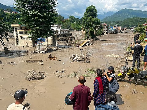 Residents look at houses partially submerged in muddy water after flash floods at Trishuli Bazar in Nepal's Nuwakot district.