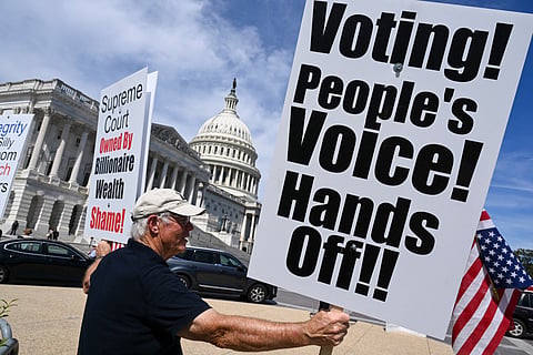 Demonstrators hold signs as they protest against US President Donald Trump's executive order that aimed to change how Americans vote by mail ahead of the midterm elections, outside the US Capitol building in Washington, DC on September 15, 2026.