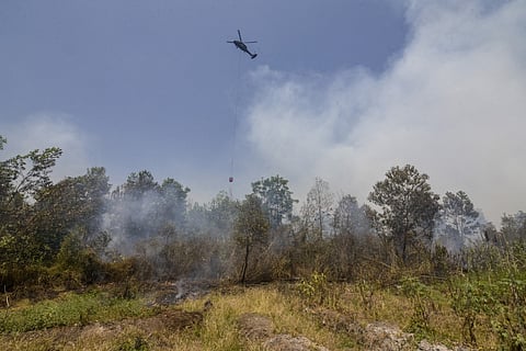 A helicopter drops water on burning forests and land in the Tegal Arum and Guntung Damar areas, Banjarbaru, in Indonesia’s South Kalimantan province on September 19, 2026.