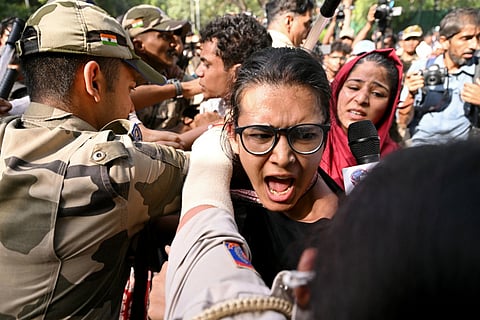 Police and security personnel detain All India Students' Association (AISA) President Neha Bora (C) during a protest against the country's Chief Election Commissioner Gyanesh Kumar in New Delhi on October 3, 2026, to demand his resignation over alleged irregularities in the Special Intensive Revision (SIR) of electoral rolls.