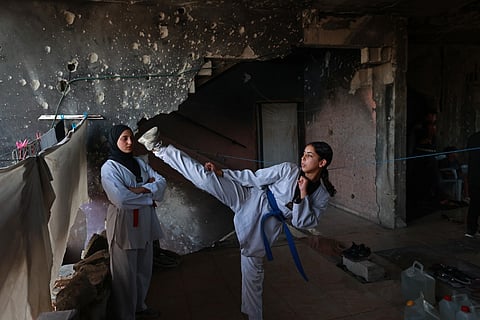 Palestinian youth take part in a Taekwondo training session inside a damaged building in Nuseirat, central Gaza Strip.