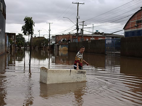A man uses a damaged refrigerator as a boat to carry groceries on a flooded street in Porto Alegre, Rio Grande do Sul, Brazil on May 26, 2024.