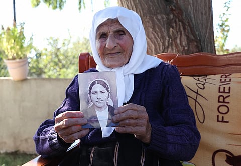 The 117-year-old Qamile Marra holds a black and white photograph from her youth during an interview with AFP in the garden of her home in the village of Ferras, near Kucove, some 80 kilometres from the capital Tirana on October 3, 2026.