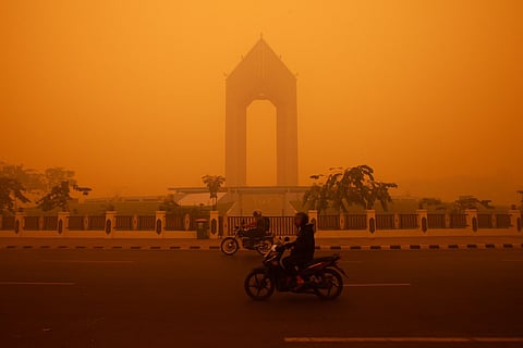 Motorcyclists ride in the morning in Palangkaraya, Central Kalimantan on October 14, 2026, amid thick haze from forest and land fires in the region.