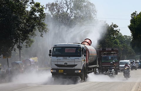 A truck-mounted water sprinkler sprays tiny droplets of water to mitigate the effects of air pollution on a road near India Gate, in New Delhi on Monday.