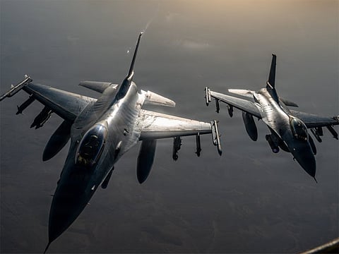 F-16 fighter jets approach a KC-135 Stratotanker to refuel while flying over the Middle East.