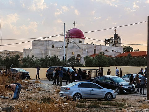 People and security forces gather outside a Greek Orthodox Church in the village of Hammoud village in Jordan's Karak governorate following a shooting on October 23, 2026.