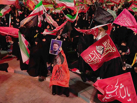Demonstrators wave flags as one holds up a portrait of the Iranian Supreme Leader Ayatollah Mojtaba Khamenei during a pro-government gathering in Tehran.