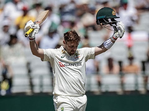 Australia's Josh Inglis raises his bat and helmet to celebrate after scoring a century on day three of the third Test match against South Africa at Newlands stadium in Cape Town on October 29, 2026.
