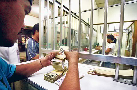 A foreign exchange house staff counts Philippine pesos.