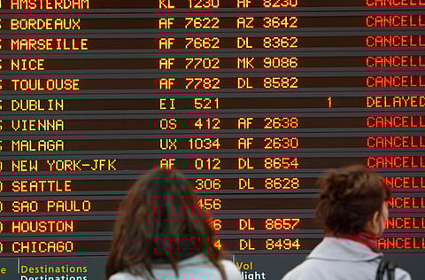 Passengers look at a departures board at Paris Roissy Airport, as hundreds of commercial flights across northern and eastern Europe are cancelled by a drifting plume of volcanic ash.