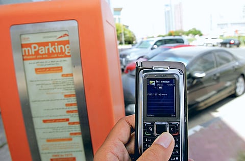 A motorist uses the mParking service by sending an SMSthrough his mobile phone at a paid parking zone on Sheikh Zayed road.