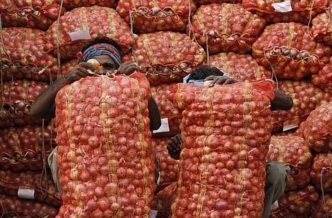 Indian labourers unload sacks filled with onions at a market on the outskirts of Allahabad, India.