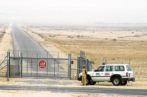 A Kuwaiti border guard is seen standing next to the security fence. The land borders between Kuwait and Saudi Arabia have been reopened following a six-month closure due to the COVID-19 pandemic.