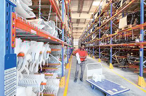 Workers collect spare parts from the racks at a facility in a Dubai industrial area.