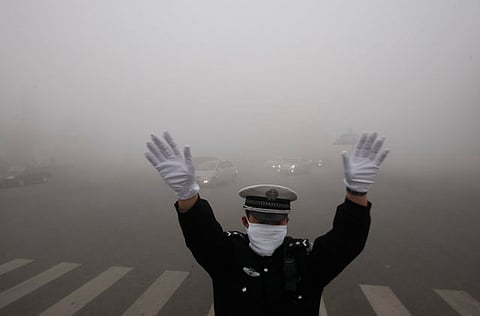 A policeman directs traffic in the heavy smog in Heilongjiang province, China (File)