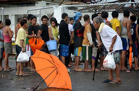 Typhoon victims queue up for relief goods in the aftermath of Super Typhoon Haiyan in Tacloban, east