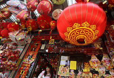 Shopper leave a shop decorated with Chinese New Year’s lanterns in the Chinatown area in Bangkok, Thailand. Thailand’s economy faces fresh turbulence after China banned outbound group tours.
