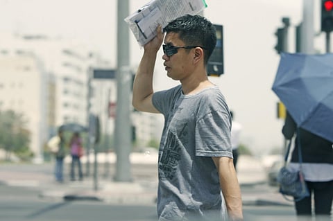 A man shields himself from the sun while taking a walk in Dubai.