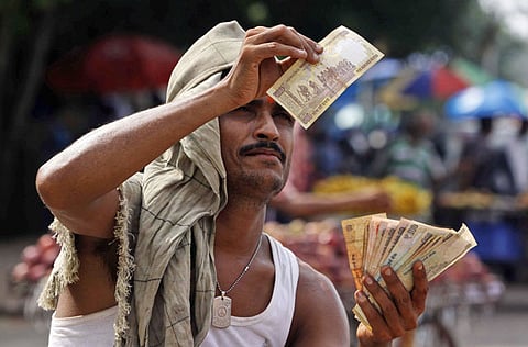 A roadside fruit vendor checks the authenticity of a 500 rupee note. As coronavirus cases continue to surge in India, restricting several economic activities, the World Bank may project a steeper contraction of the Indian economy for the current financial year.