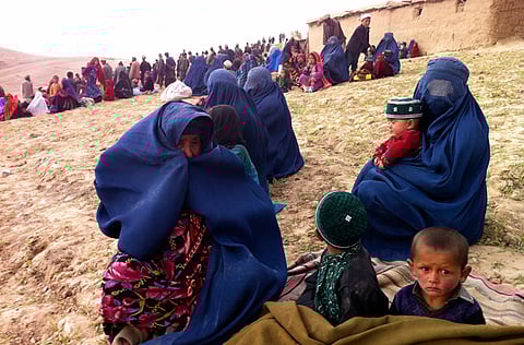 In this file picture from 2014, survivors sit on a hillside as others watch the rescue effort near the site of Friday's landslide that buried Abi-Barik village in Badakhshan province, northeastern Afghanistan, Saturday, May 3, 2014.