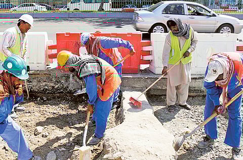 Workers at a road project in Abu Dhabi. The midday break aims to prevent labourers from toiling under direct sunlight between 12.30 and 3pm.