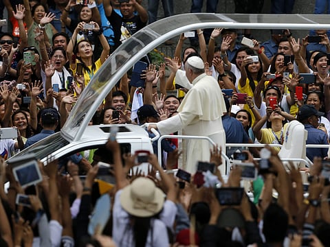 Pope Francis on a 'popemobile' waves to Filipino well wishers at a street to lead a mass at the Manila cathedral, Philippines, 16 January 2015.