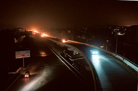 Motorists drive on an unlit street during a power cut in Karachi (File)