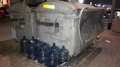 Water bottles placed next to garbage bin