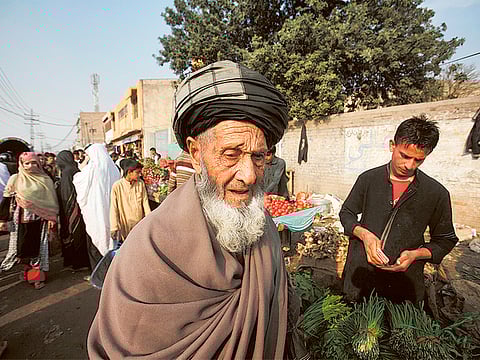 An elderly Afghan refugee walks along a market in Peshawar, Pakistan.