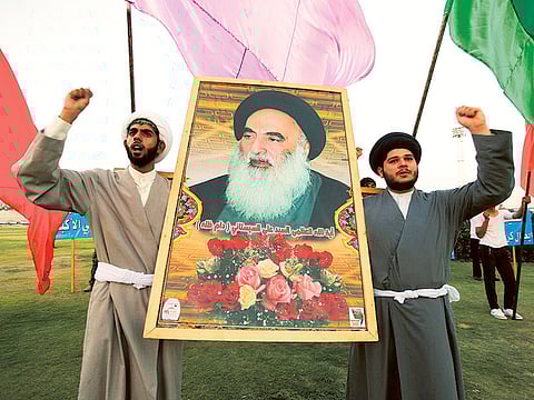 Shiite army volunteers with a picture of Grand Ayatollah Ali Al Sistani at a graduation ceremony after completing their training.