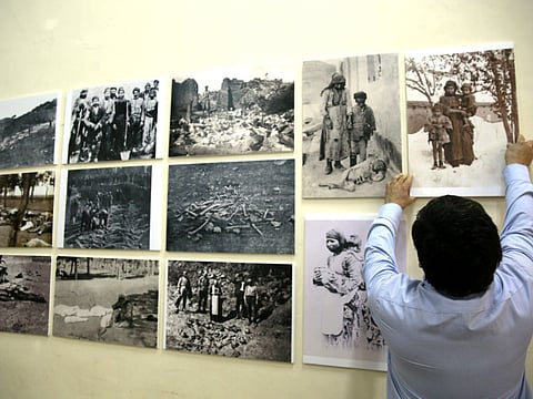 Armenian Serop Sahagian, the head of the Homenetmen Club, hang pictures to be displayed in an exhibition marking the 100th anniversary of the mass killings of Armenians under the Ottoman Empire in 1915, on April 17, 2015 in the Armenian Quarter in Jerusalem's Old City. Armenians around the world will mark on April 24, 2015 the centenary of the World War I-era mass killings of their kin by Ottoman Turks in what they insist was a genocide -- a term fiercely rejected by Turkey. AFP PHOTO / GALI TIBBON