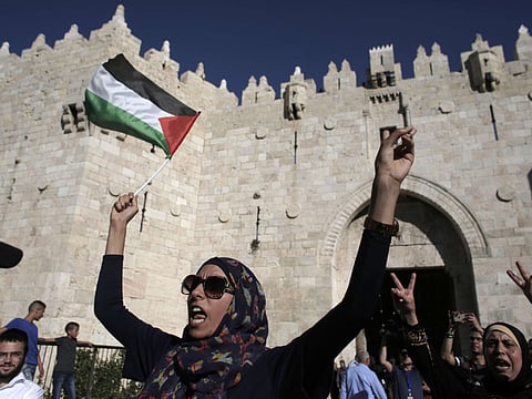 A Palestinian woman holds up a national flag as she demonstrates outside Damascus Gate in Jerusalem's old city on May 17, 2015, against the "flag march" attended by Israeli nationalists to mark the 48th anniversary of the capture of Arab east Jerusalem in the Six Day War of 1967. Known as Jerusalem Day, the anniversary marks Israel's seizure and later annexation of the territory, which includes the walled Old City, in a move never recognised by the international community.