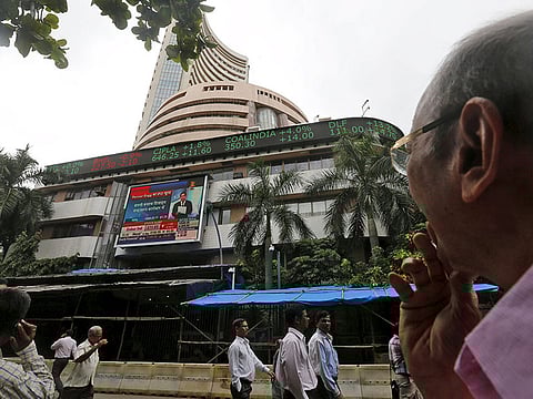 A man (R) watches a large screen displaying India's benchmark share index on the facade of the Bombay Stock Exchange (BSE). Like in other major markets, earnings in India weren’t as bad as feared as companies slashed costs to save cash.