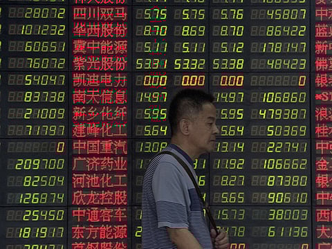 An investor walks past a digital board showing stock market movements at a brokerage house in Shanghai. Stocks in China plummeted, as trade resumed post-holidays, the move was not as bad as feared.