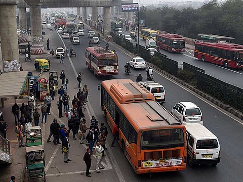 Commuters board buses in New Delhi.